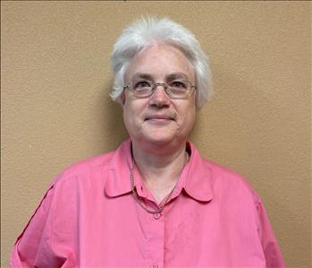 White female with white hair, wearing a pink shirt and glasses