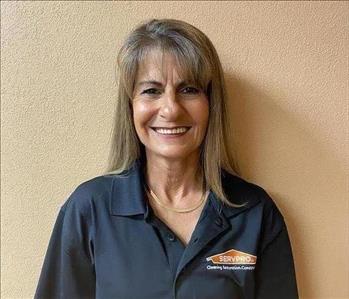 white female with long brown hair wearing a black SERVPRO polo