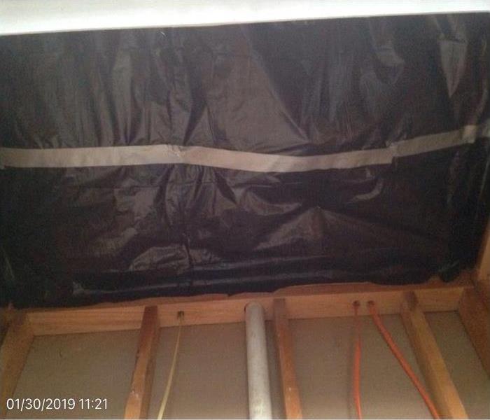 wooden structure beams holding wall up, tarp tapped together to create enclosed space for drying