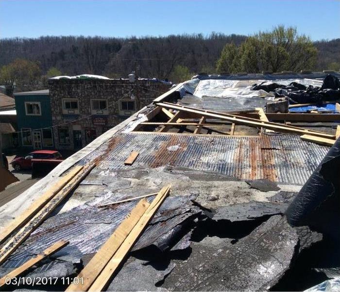 extensive roof damage, top view of building showing rusted roof top with missing pieces 