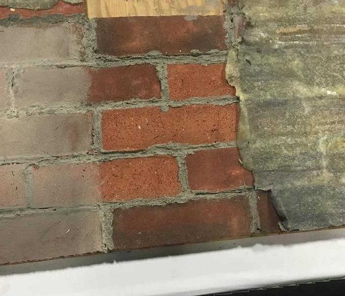 red bricks covered in soot after fire damage, the right shows the before, in the middle is after we removed the soot