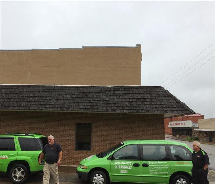 two crew memebers leaving SERVPRO vehicles, a commerical building is behind them
