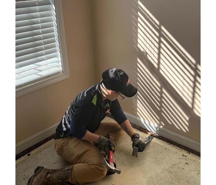 man doing demolition on floor after a flood has dried up in home