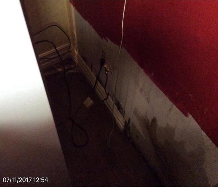 water damage behind ice maker in a dark space, red walls, white on the bottom