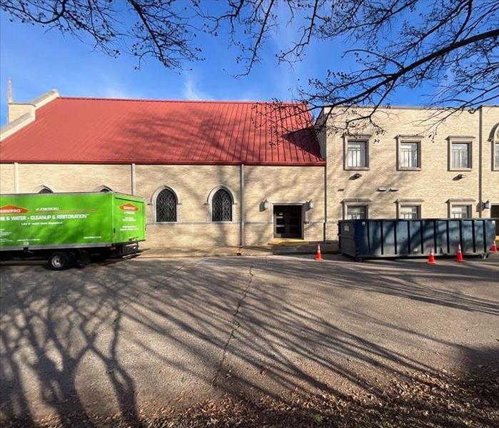 side of church building with SERVPRO truck to the left and right with a roll off dumpster in the middle 