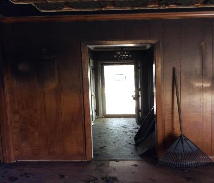 badly burned home, upper walls covered in black soot with a rake next to the entrance