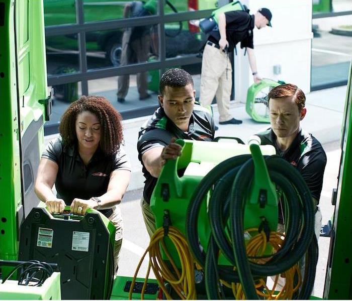 three SERVPRO employees unloading equipment out of a green van